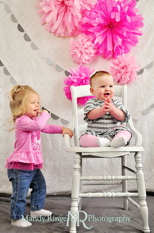 Baby girl's first birthday photo shoot. Sitting on a white chair. Pink tissue paper poms, gray paint chip garland // Pink, gray and white birthday // by Mandy Ringe Photography