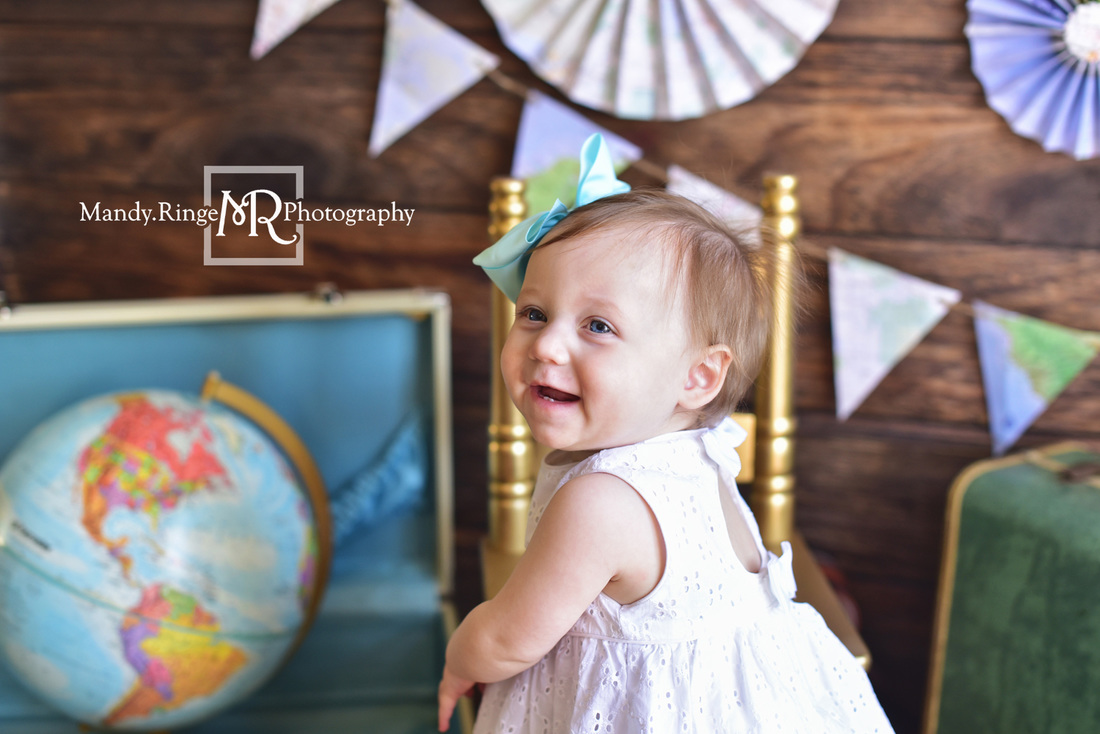 Little Traveler first birthday portraits // World traveler, maps, globe, suitcases, pennant banner, paper fans, little girl, passport // Traveling studio - client's home, Batavia, IL // by Mandy Ringe Photography