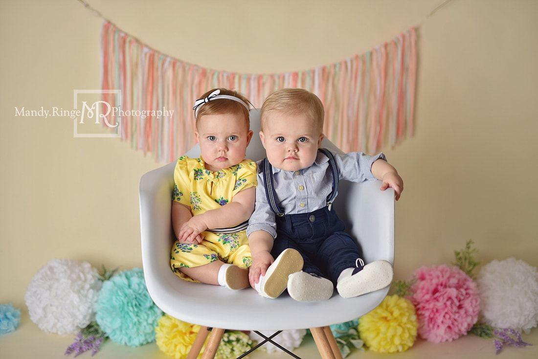 Boy and girl twins first birthday portraits // pastel, rainbow, colorful, spring, flowers, puffs, poofs, ribbon garland, white chair // by Mandy Ringe Photography // St. Charles, IL Photographer