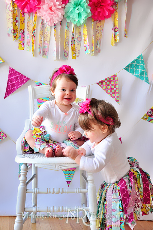 Twin girl's first birthday portraits // White chair, fabric pennants, rag banner, rag skirt, pink, teal, fuchsia, yellow, tissue paper pom poms // by Mandy Ringe Photography