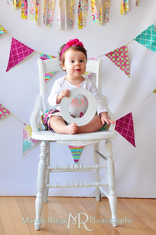 Twin girl's first birthday portraits // White chair, fabric pennants, rag banner, rag skirt, pink, teal, fuchsia, yellow, holding letters to spell ONE // by Mandy Ringe Photography