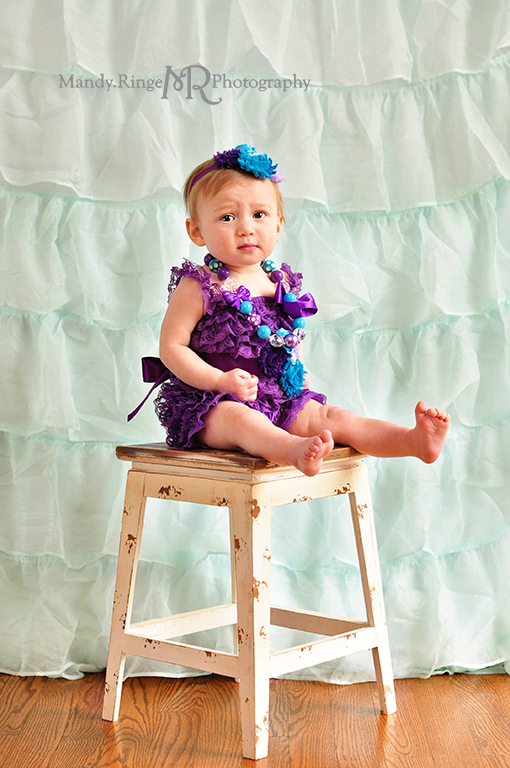 Baby girl's first birthday portraits // Purple, teal and aqua // Aqua ruffle backdrop, purple ruffle romper, fabric flower headband, chunky necklace // by Mandy Ringe Photography