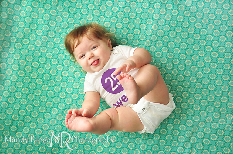 Weekly photos of a baby girl for the first year // Laying on a fabric backdrop, photoshopped numbers on white onesies // by Mandy Ringe Photography