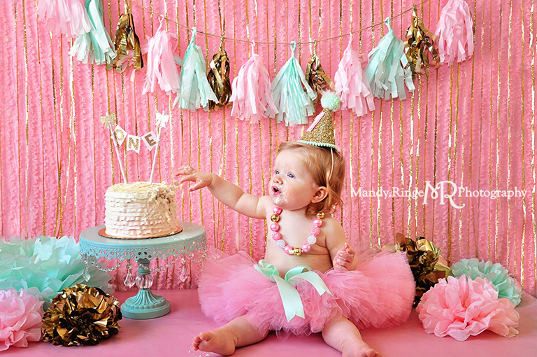 Pink, gold, and mint first birthday // Smash cake session // Tassle garland, tissue poms, pink ruffle fabric backdrop, gold sequin strands // St Charles, IL // by Mandy Ringe Photography