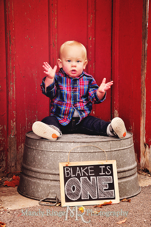 1 year old boy sitting on a wash tub in front of a red barn with chalkboard // First birthday portraits // Leroy Oaks - St Charles, IL // by Mandy Ringe Photography