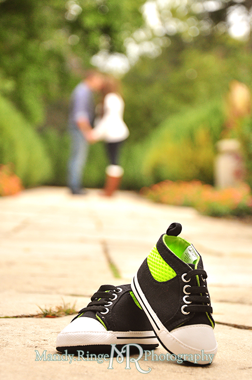 Baby shoes in focus in the foreground with man and woman blurred and kissing in the background // Maternity portraits // Hurley Gardens - Wheaton, IL // by Mandy Ringe Photography