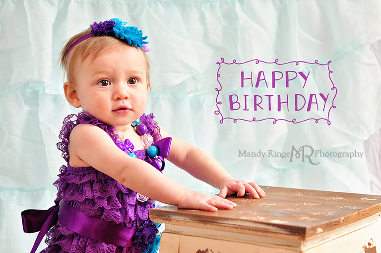 Baby girl's first birthday portraits // Purple, teal and aqua // Aqua ruffle backdrop, purple ruffle romper, fabric flower headband, chunky necklace // by Mandy Ringe Photography