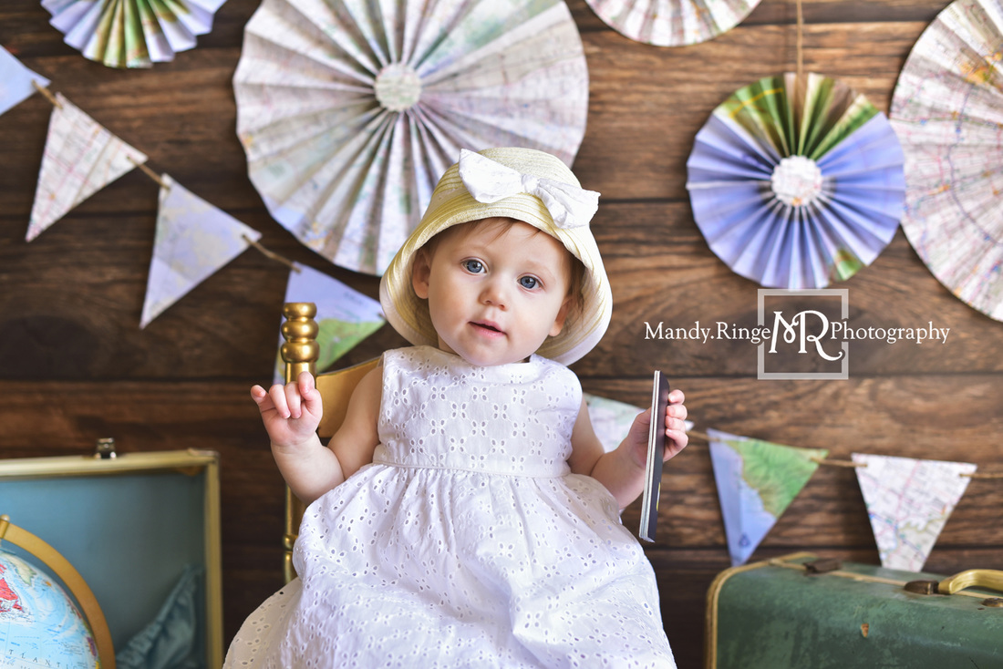 Little Traveler first birthday portraits // World traveler, maps, globe, suitcases, pennant banner, paper fans, little girl, passport // Traveling studio - client's home, Batavia, IL // by Mandy Ringe Photography